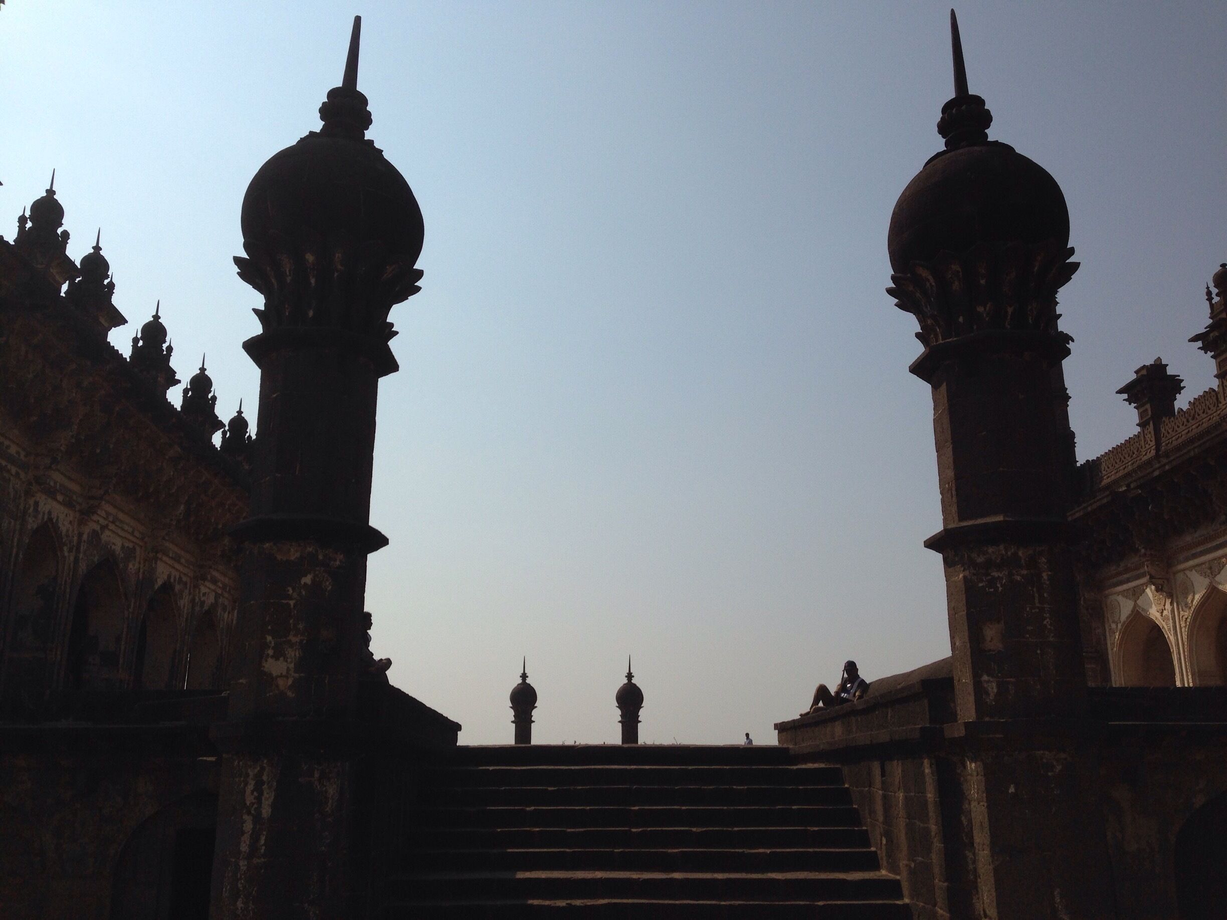 A grand entrance with ornate domes and a staircase leading up to a distant tower.