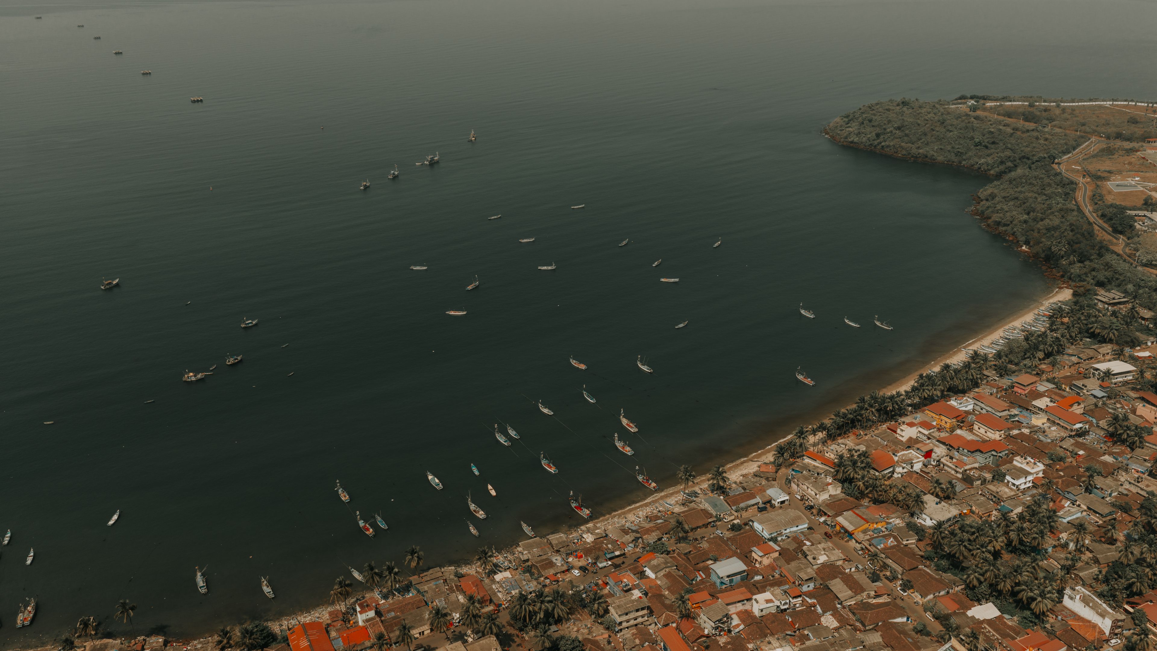 A coastal town with numerous boats anchored in the water and a dense cluster of buildings along the shore.