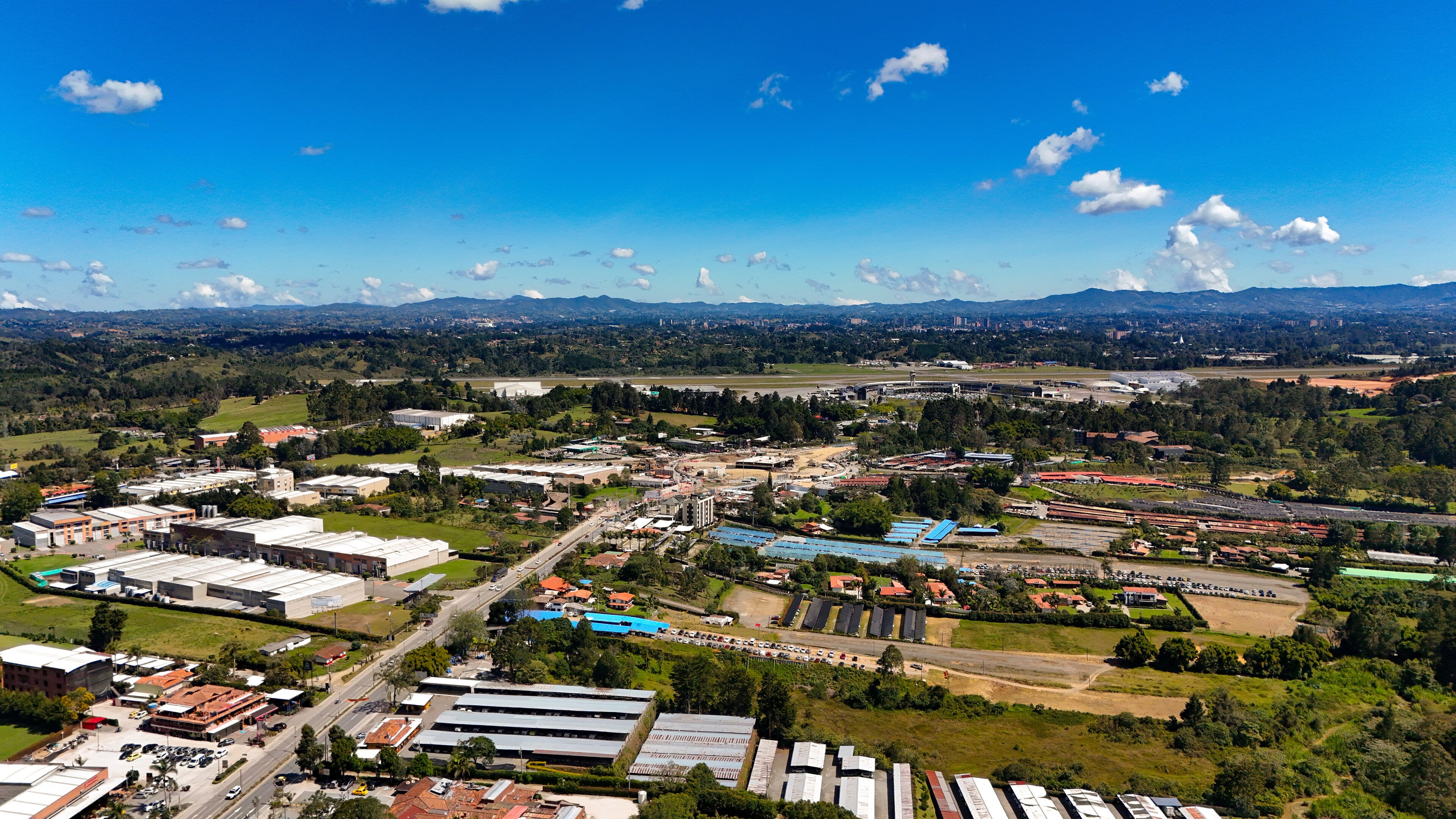 An aerial view of a city with industrial buildings, roads, and green areas.