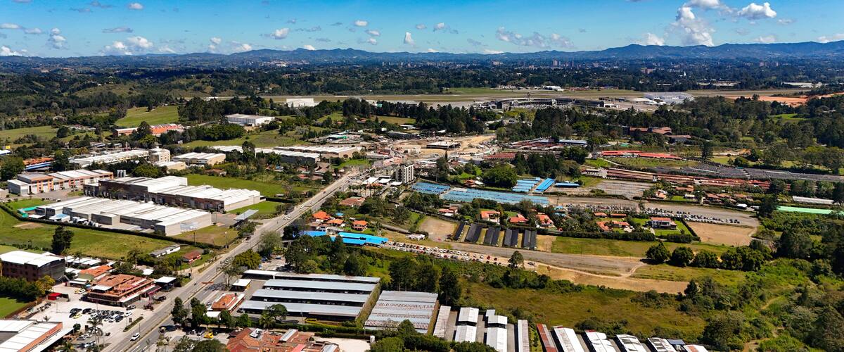 An aerial view of a city with industrial buildings, roads, and green areas.