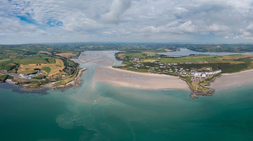 Un paisaje costero con una playa arenosa, un pueblo pequeño y un río.