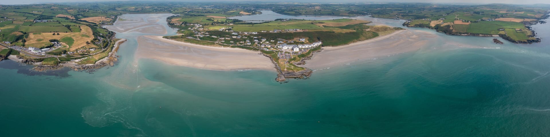 A coastal landscape with a sandy beach, a small town, and a river.