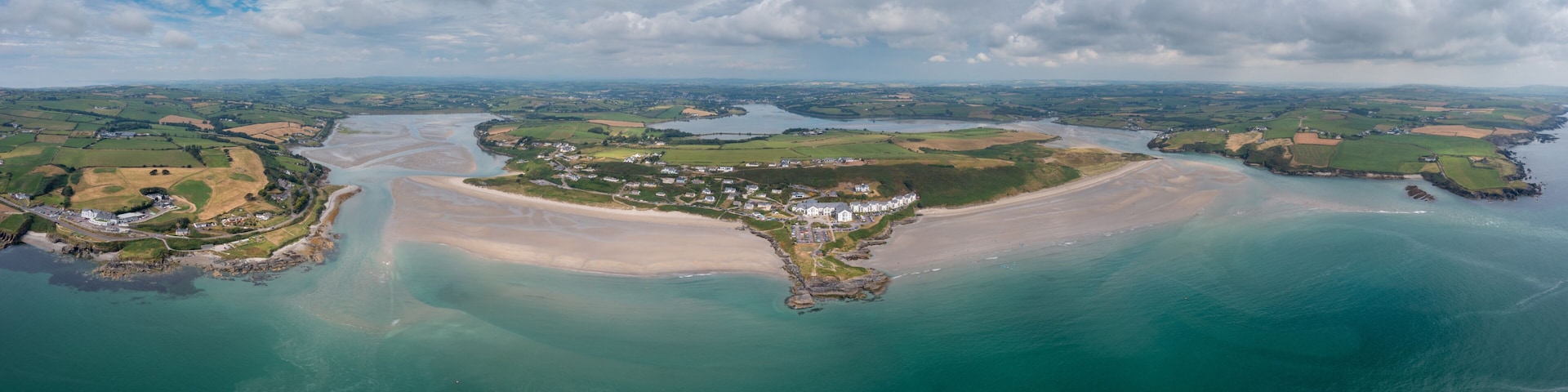 A coastal landscape with a sandy beach, a small town, and a river.