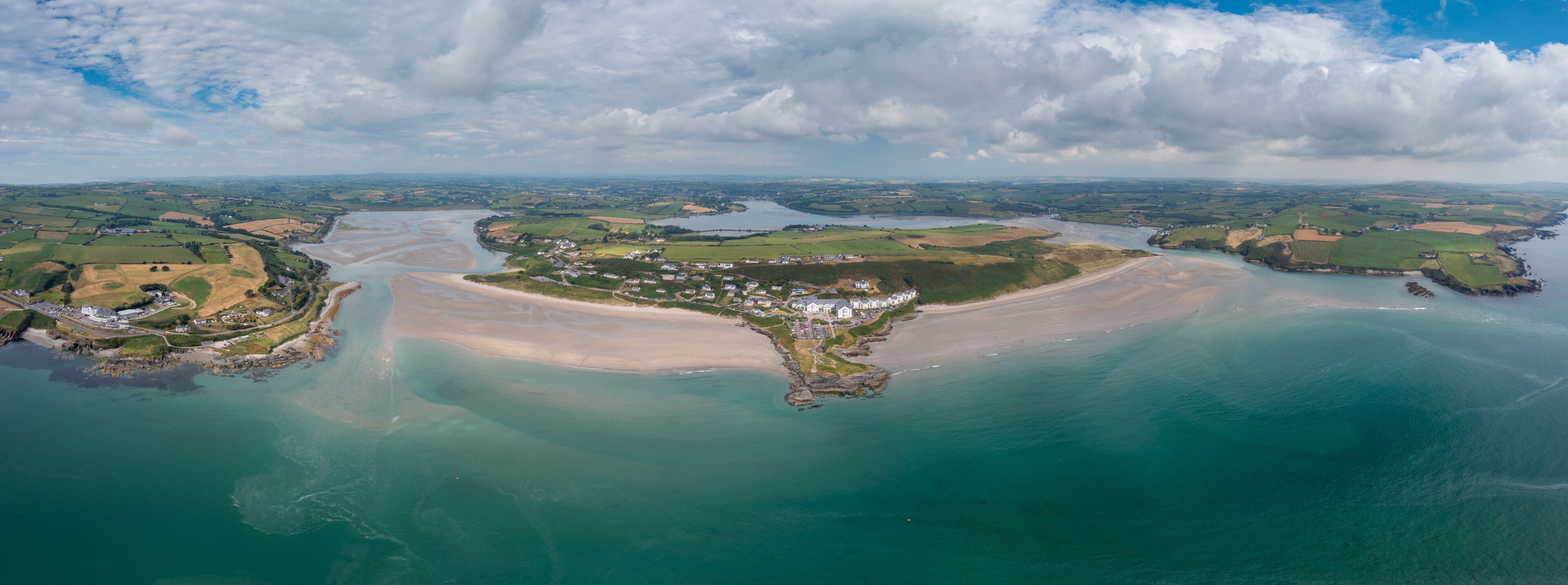 A coastal landscape with a sandy beach, a small town, and a river.