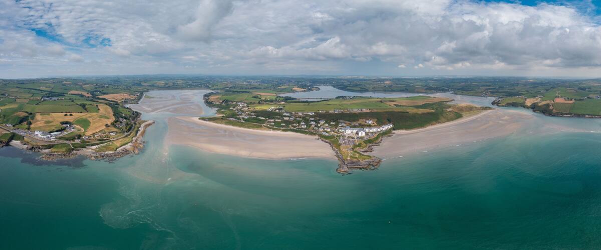 A coastal landscape with a sandy beach, a small town, and a river.
