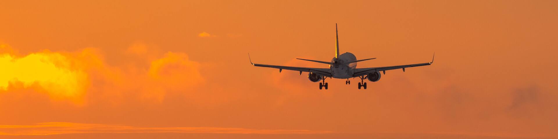 An airplane landing on a runway during sunset.