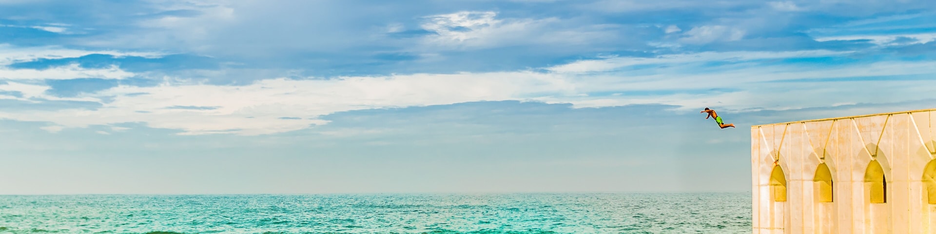 People jumping in Mediterranean sea next to Hassan II Mosque