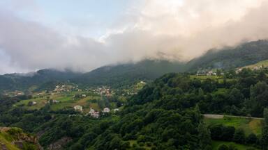 A valley with scattered houses, dense greenery, and a misty mountain backdrop.