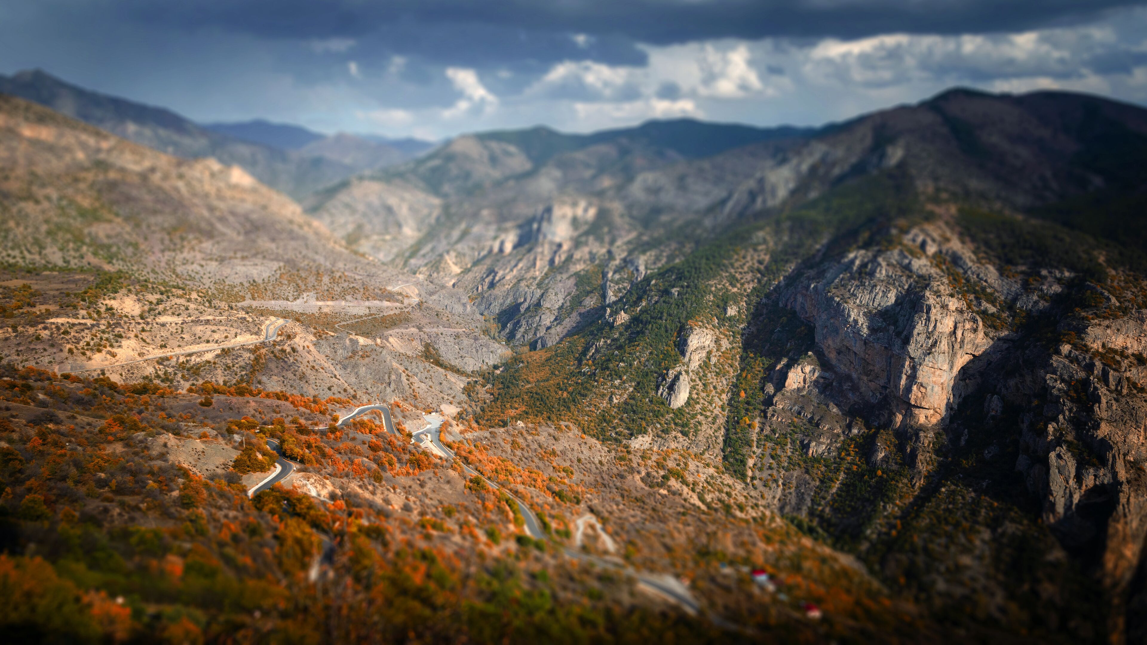A mountainous landscape with winding roads and autumn foliage.