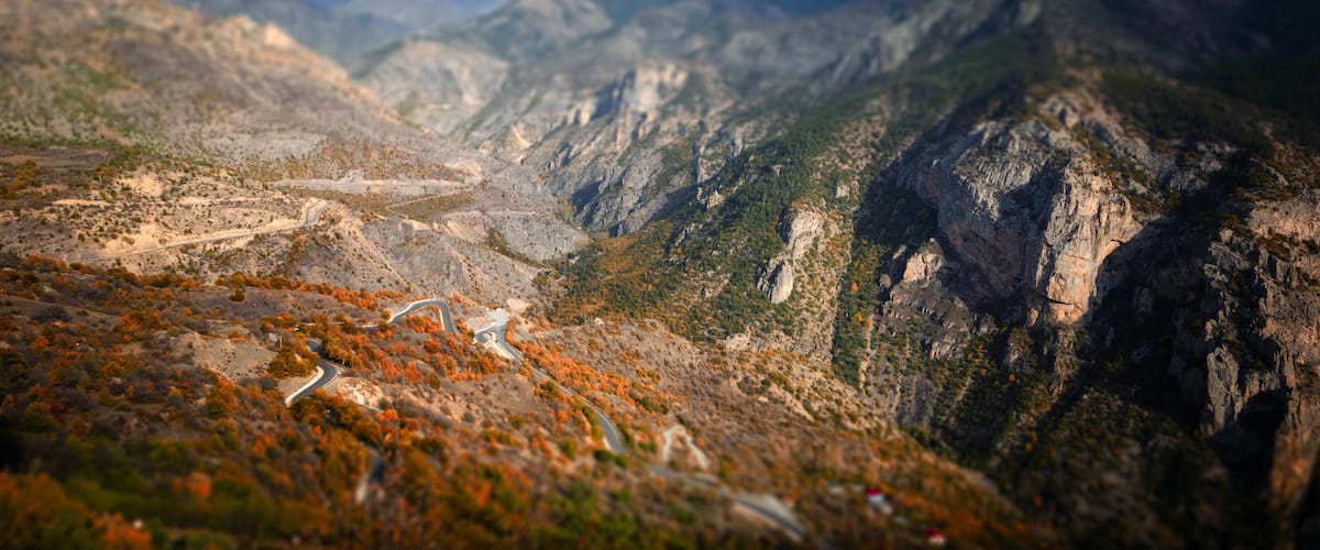 A mountainous landscape with winding roads and autumn foliage.