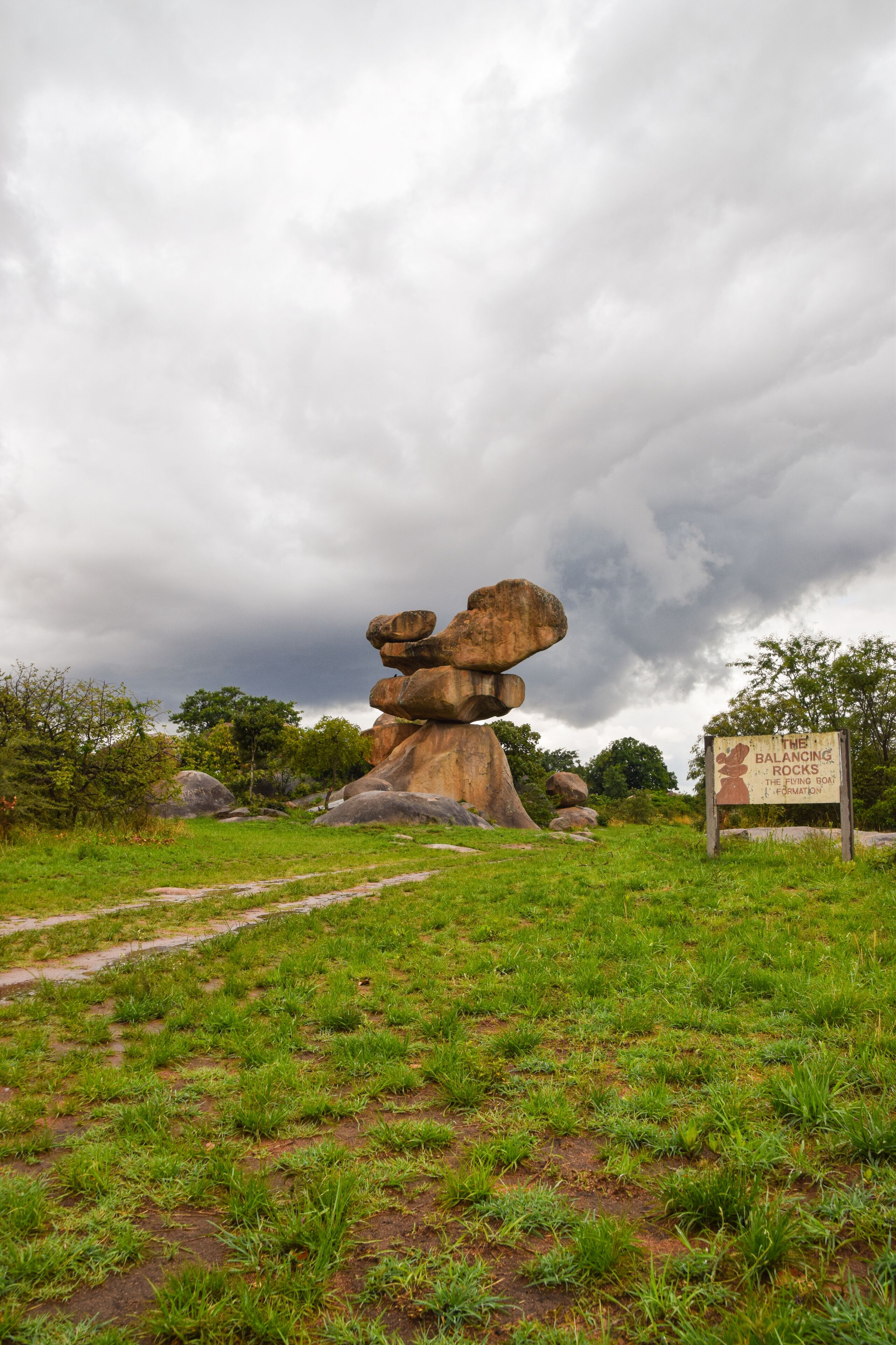 A large balancing rock formation with a sign in the foreground.