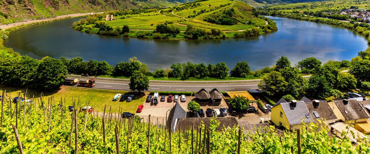 A lake surrounded by green hills, a road, and a small village with houses.