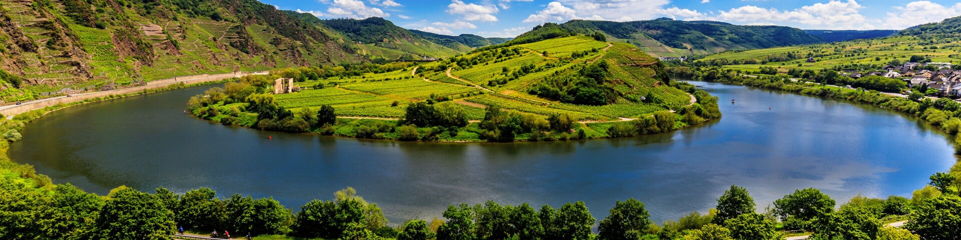 A lake surrounded by green hills, a road, and a small village with houses.