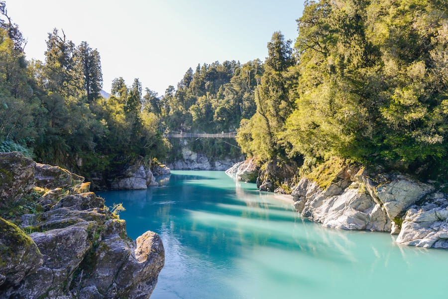 Ein türkisfarbener Fluss, umgeben von felsigem Gelände und dichtem Wald.