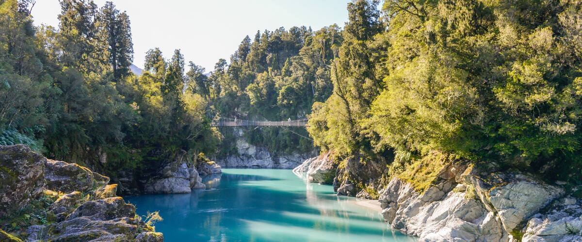 A turquoise river surrounded by rocky terrain and dense forest.