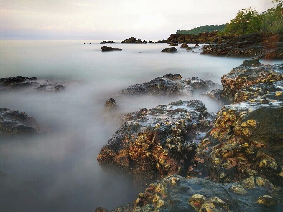 A coastal landscape with rocky formations and calm sea.