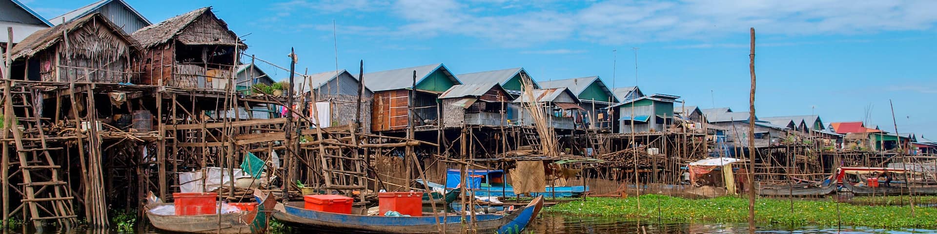 See Tonle Sap in Kambodscha: Panorama von Häusern im Wasser auf Stelzen mit grünen Wasserpflanzen