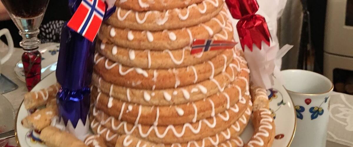 A large gingerbread house with Norwegian flags and a red ribbon.