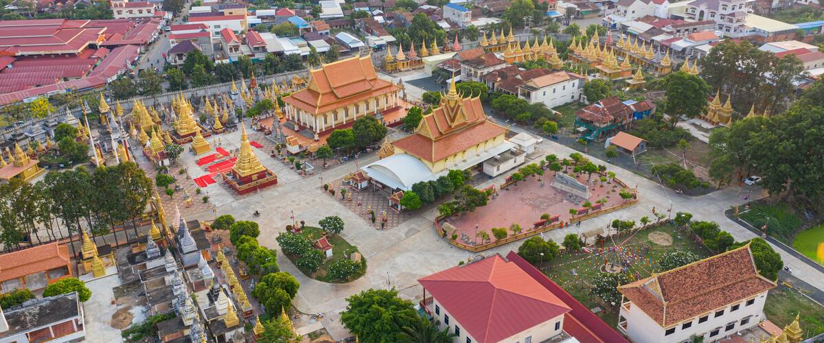 An aerial view of a town with a prominent temple complex featuring golden spires and a large white building with a red roof.