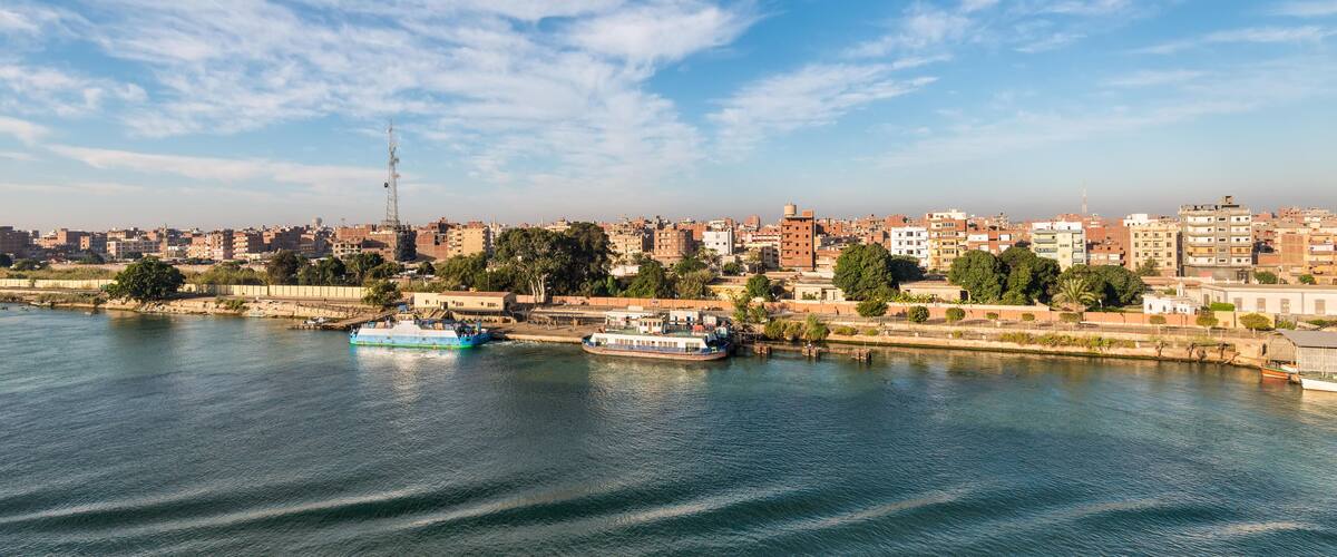 A river with boats, a cityscape, and a clear sky.
