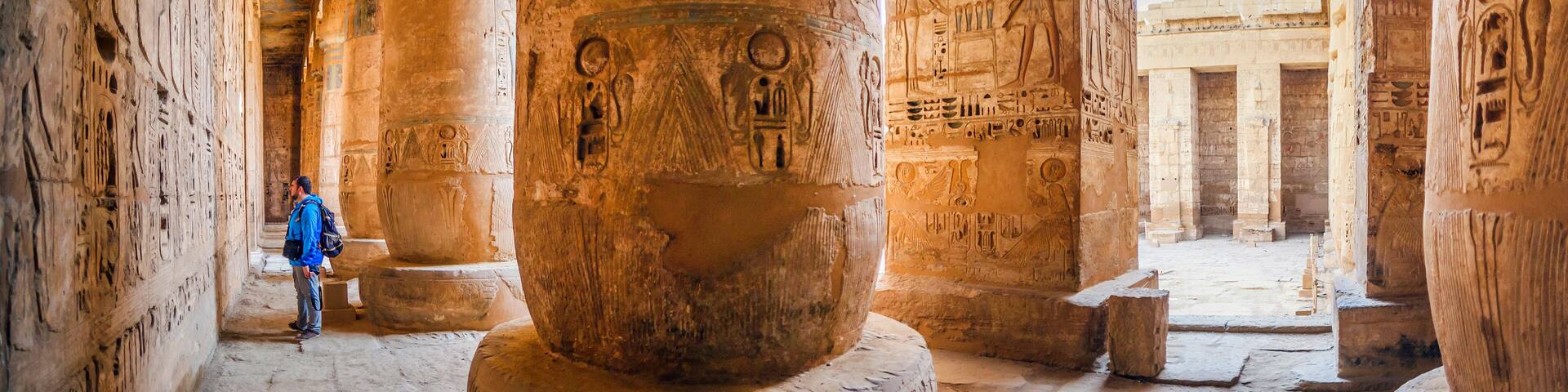 The tourist considers the hieroglyphs on the walls of the temple of Medinet Habu. Egypt, Luxor. The Mortuary Temple of Ramesses III at Medinet Habu is an important New Kingdom period structure