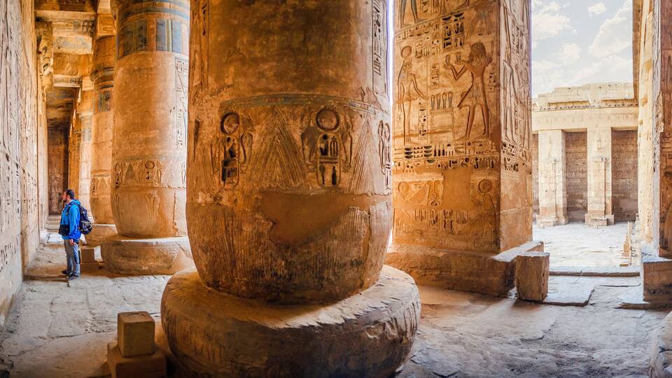The tourist considers the hieroglyphs on the walls of the temple of Medinet Habu. Egypt, Luxor. The Mortuary Temple of Ramesses III at Medinet Habu is an important New Kingdom period structure
