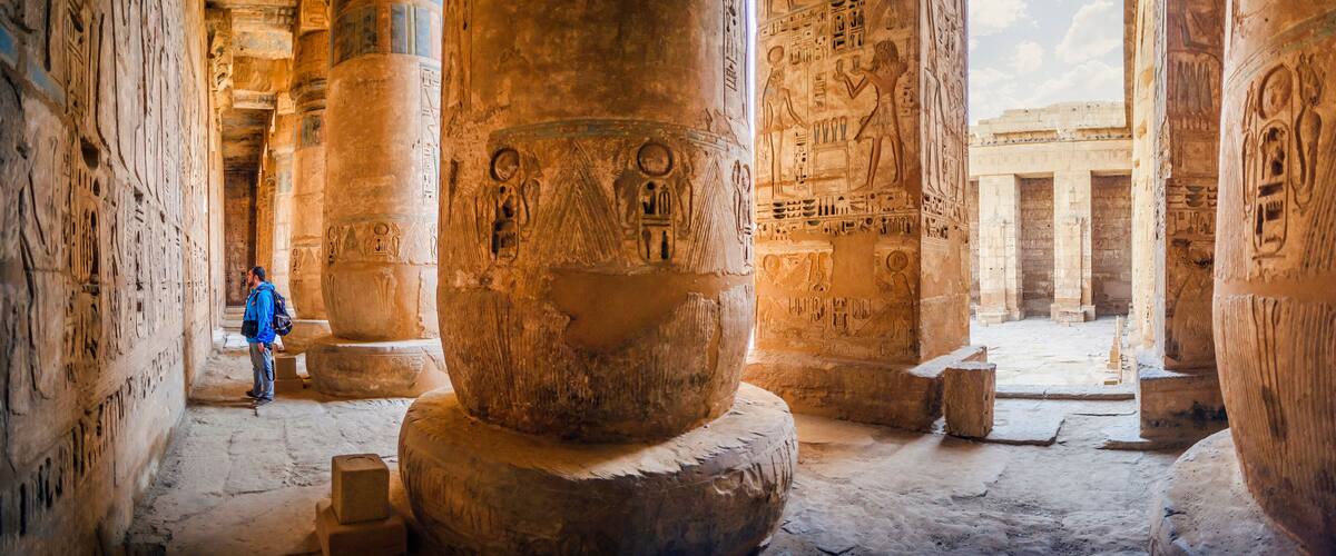 An ancient Egyptian temple interior with large stone columns and hieroglyphs.