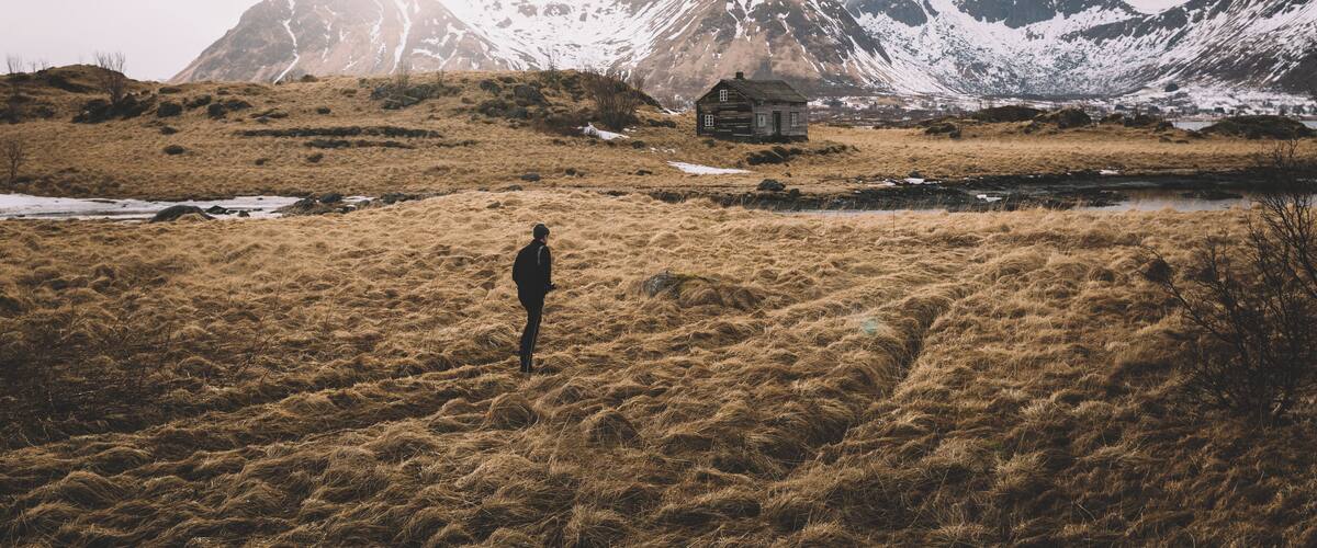 A person standing in a grassy field with a mountain in the background.