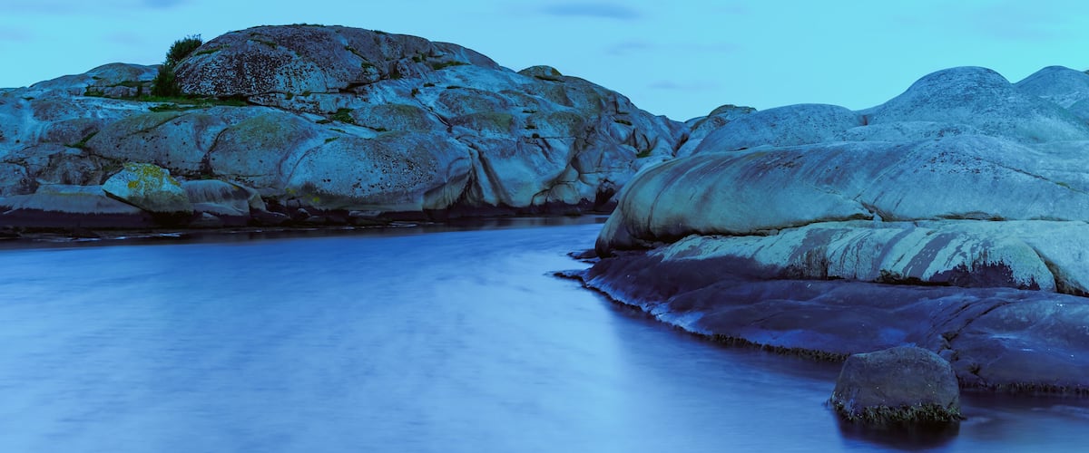 A rocky shoreline with large boulders and a calm sea.