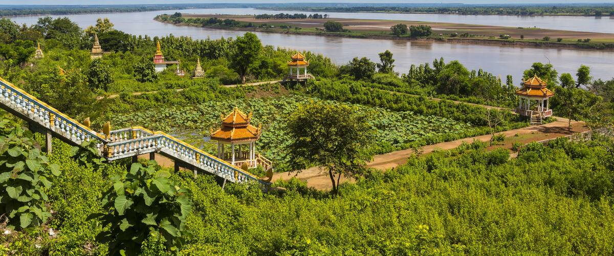 A lush green landscape with a river, lotus ponds, and traditional yellow-roofed pavilions.