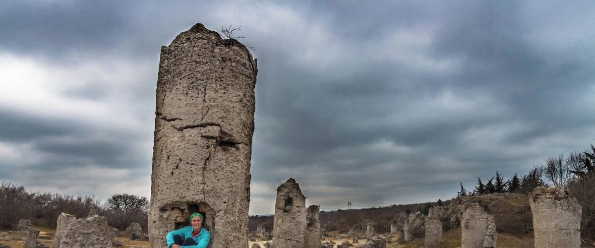 A person sitting on a stone structure in a field of similar stone structures.