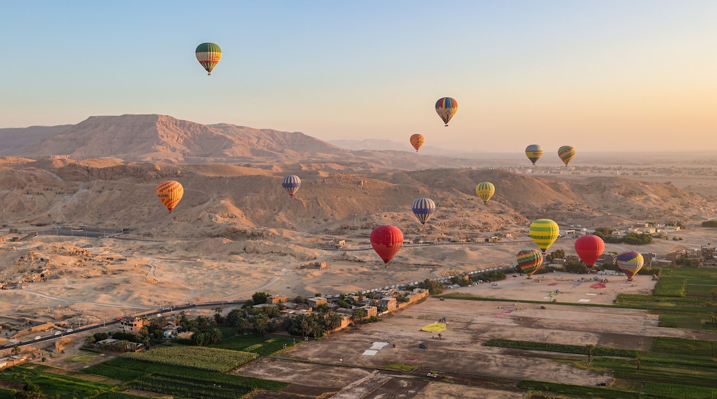 A desert landscape with multiple hot air balloons in the sky and a small town below.