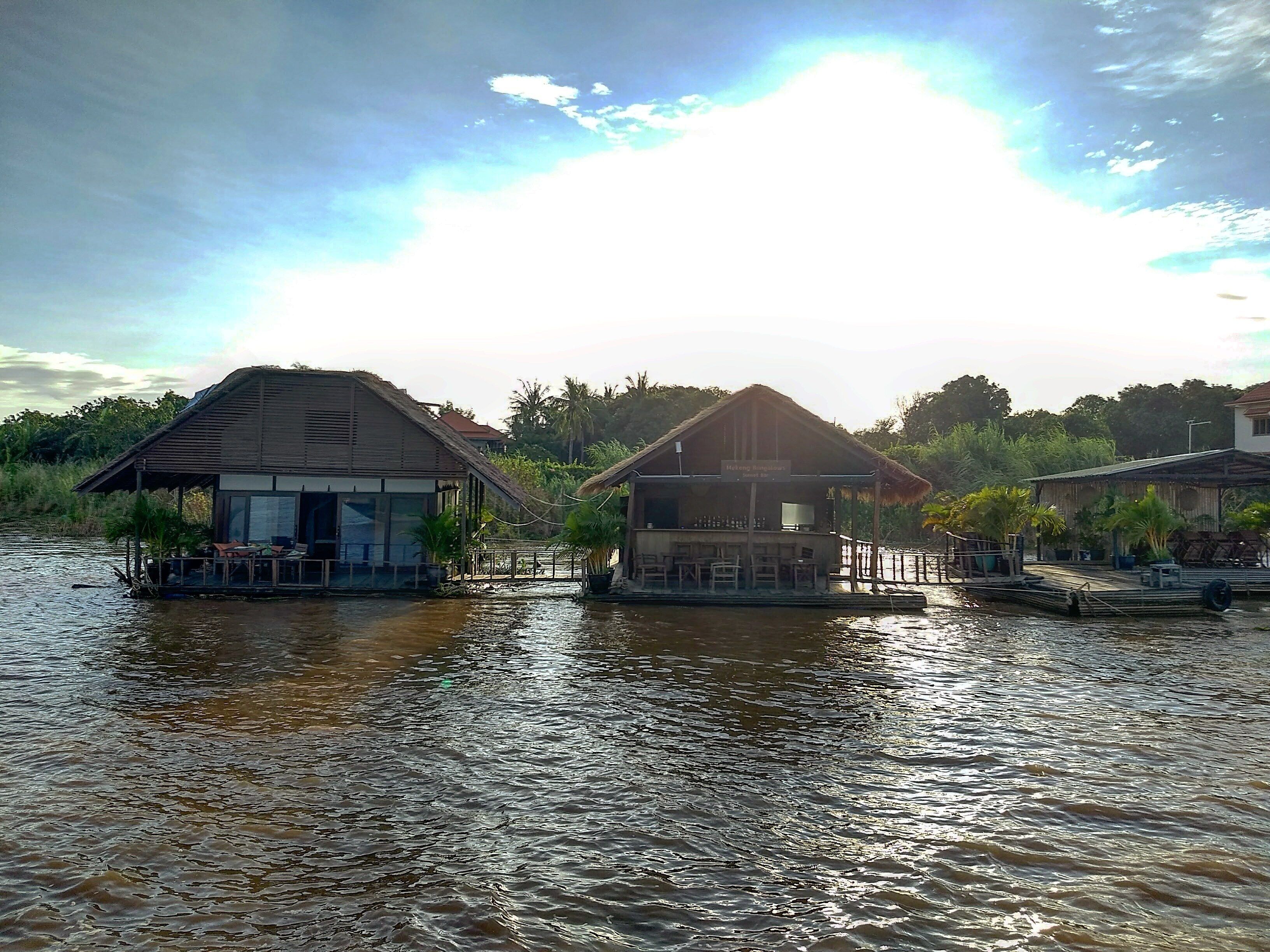 Floating houses on a river with a clear sky.