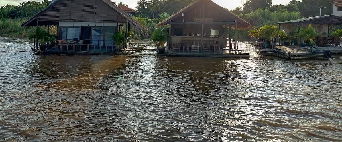 Floating houses on a river with a clear sky.