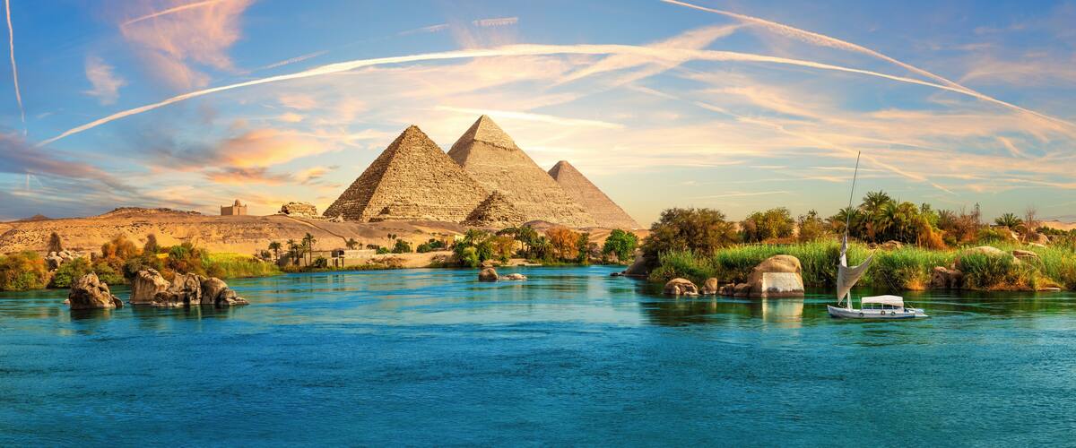 Lonely Saleboat in the Nile river and ancient rocks in the Aswan desert by the pyramids, Egypt