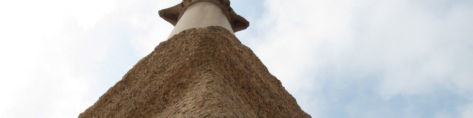 Uma torre de pedra com telhado pontiagudo sob um céu nublado.