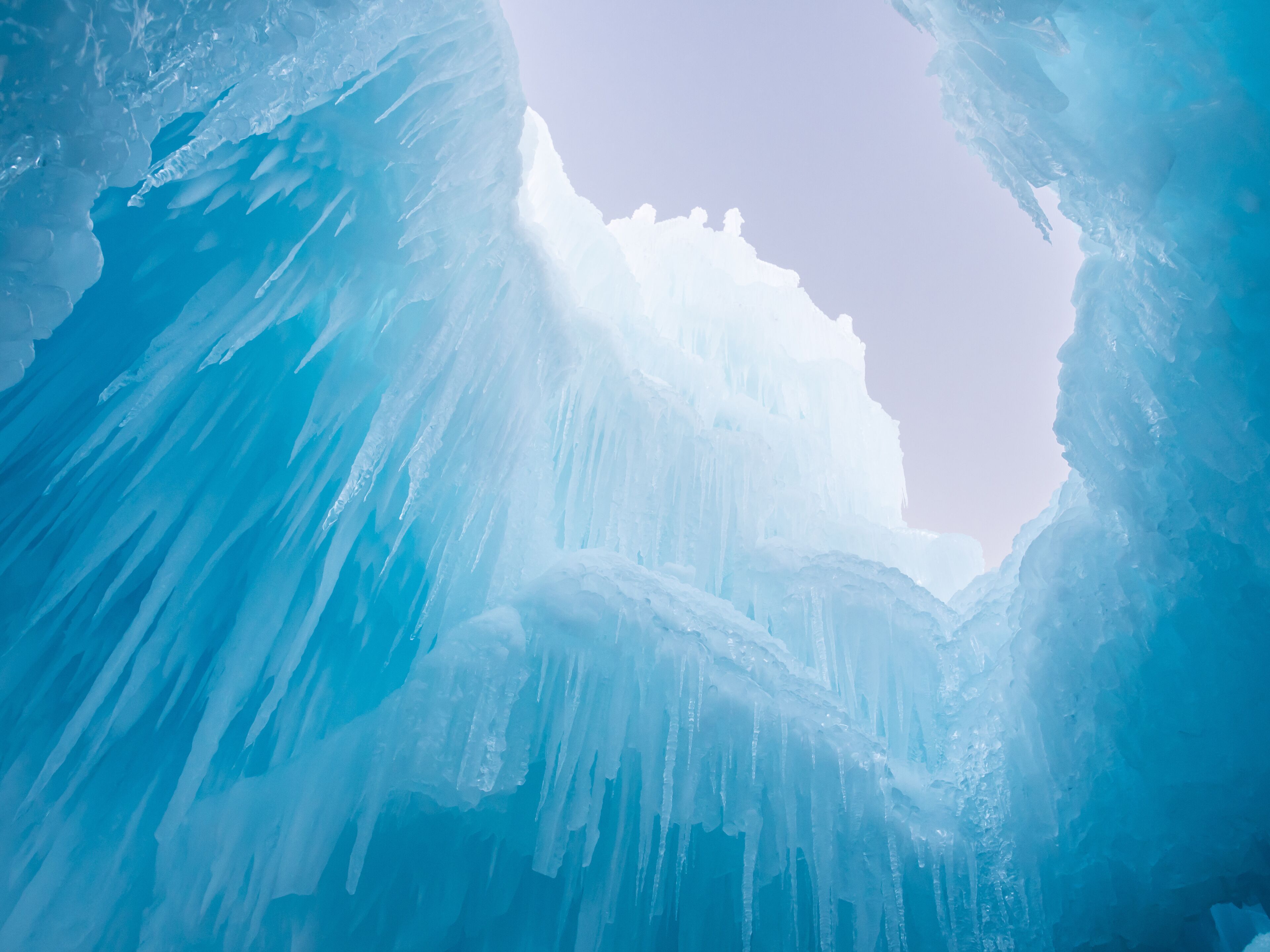 Winter ice castle caves with frozen icicles at sunset.