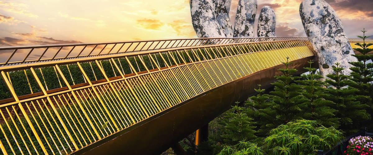Golden Bridge Hands of God at the Sun World Ba Na Hills park in Da Nang on the mountain at sunset in summer in Vietnam