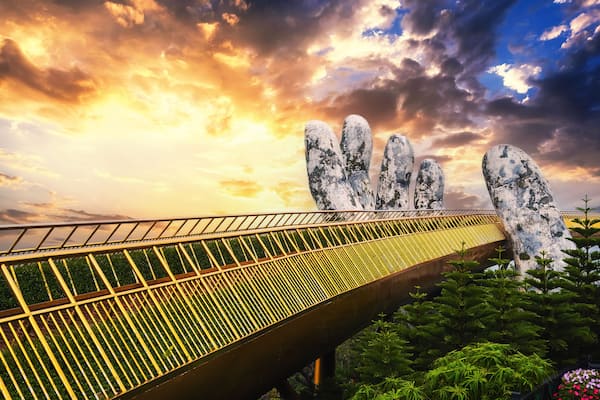 Golden Bridge Hands of God at the Sun World Ba Na Hills park in Da Nang on the mountain at sunset in summer in Vietnam