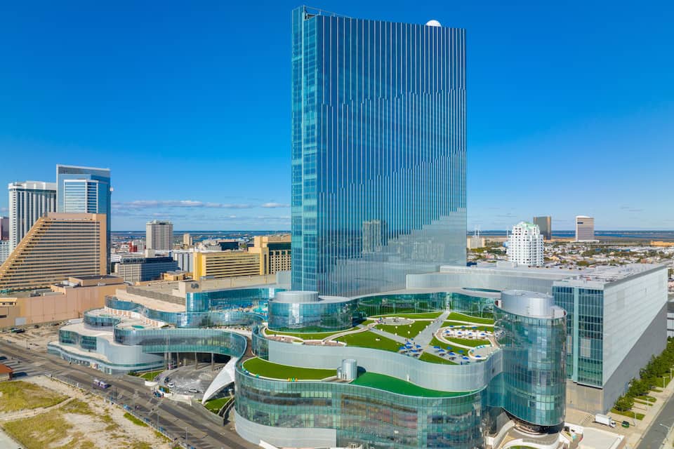 Un paisaje urbano moderno con un rascacielos destacado, un edificio de vidrio curvo y vistas al mar.
