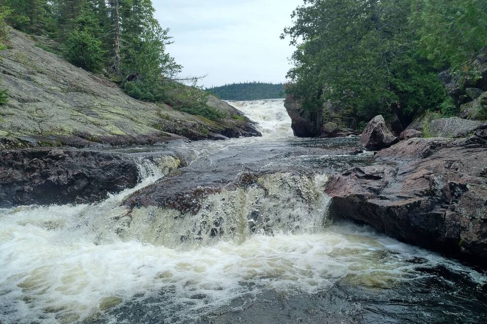 En flod der snor sig gennem en stejl kløft med tæt skov på begge sider.
