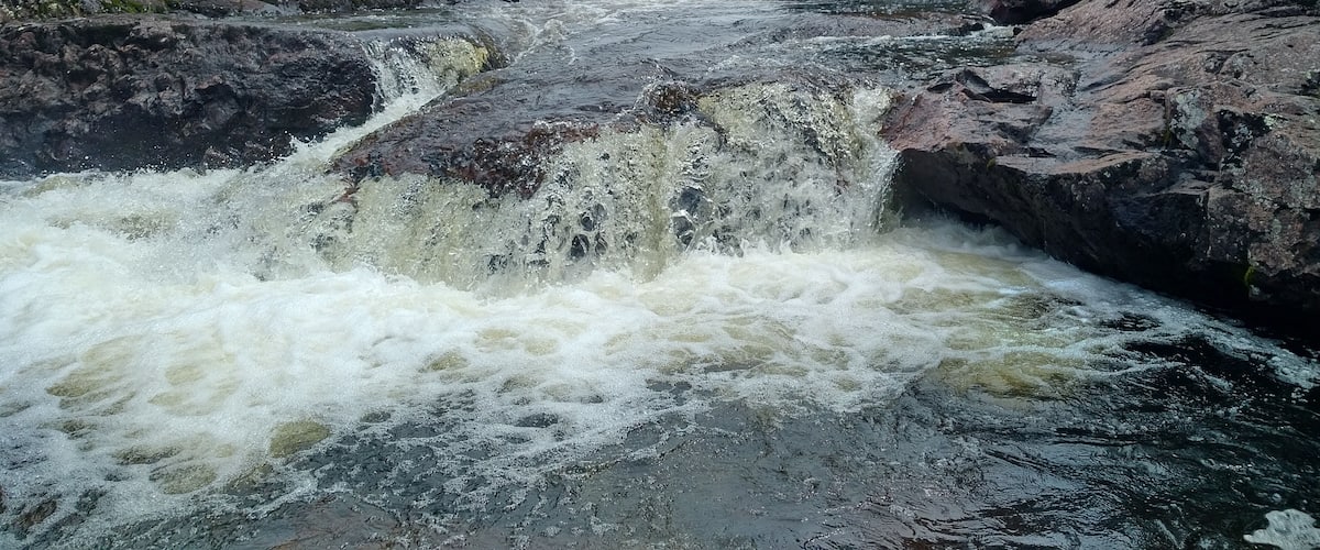 A river flowing through a rocky gorge with dense forest on either side.