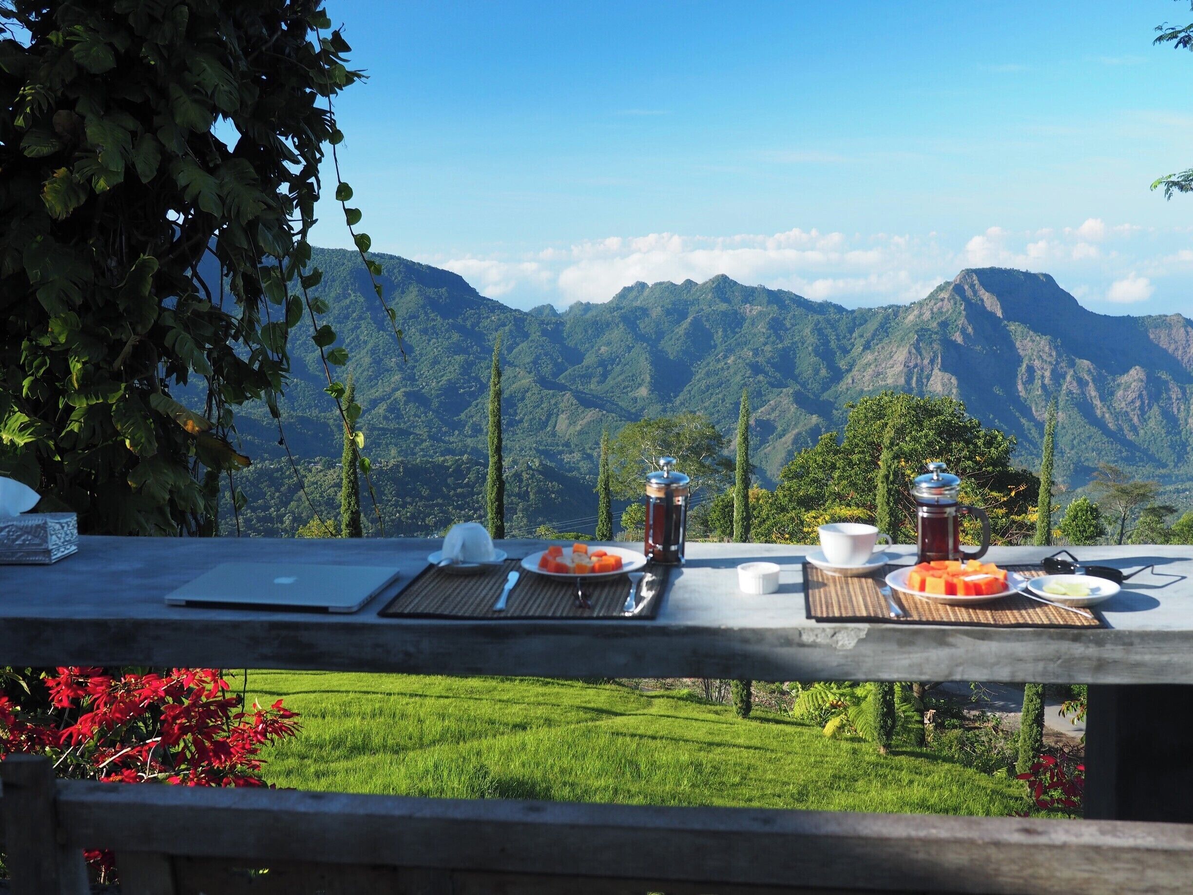 A table with food and drinks, overlooking a mountainous landscape.