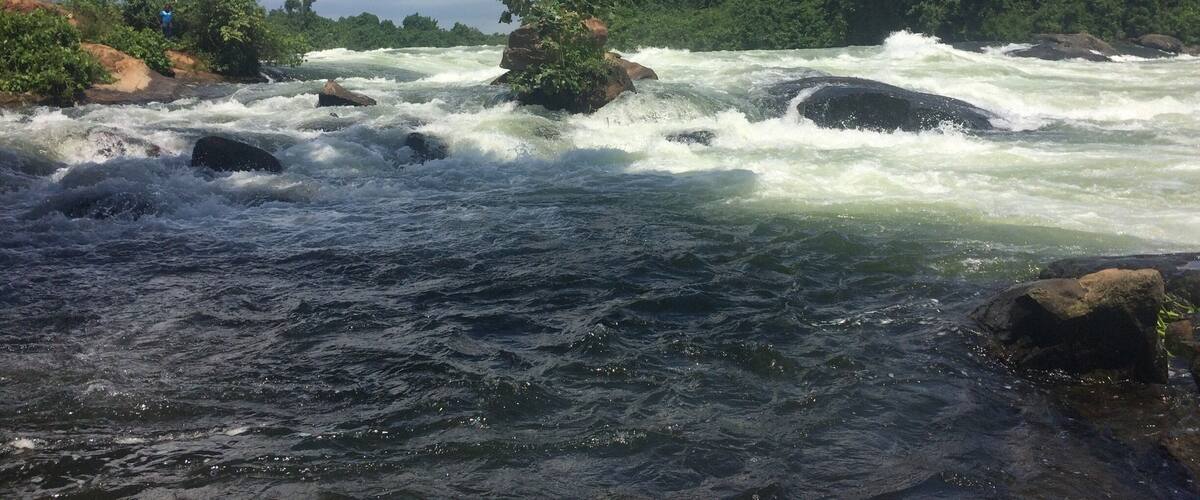 A river with fast-moving water, surrounded by rocks and greenery.