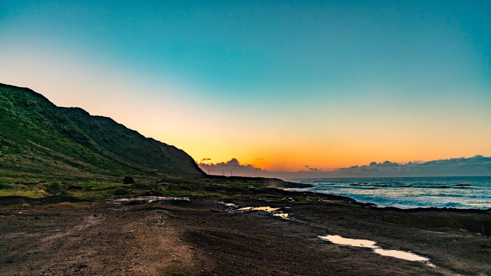 A coastal landscape with a dirt path, rocky terrain, and a body of water.