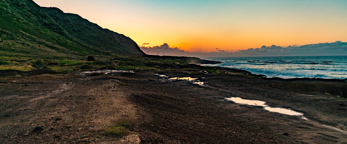 A coastal landscape with a dirt path, rocky terrain, and a body of water.
