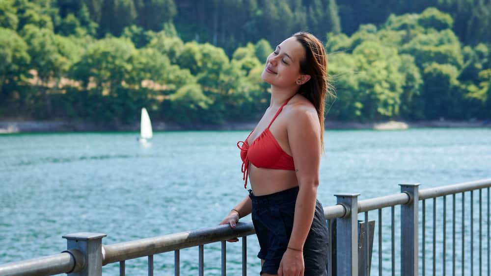 Beautiful young lady smiling with trees in the background in Lac de la Haute-Sure, Luxemburg