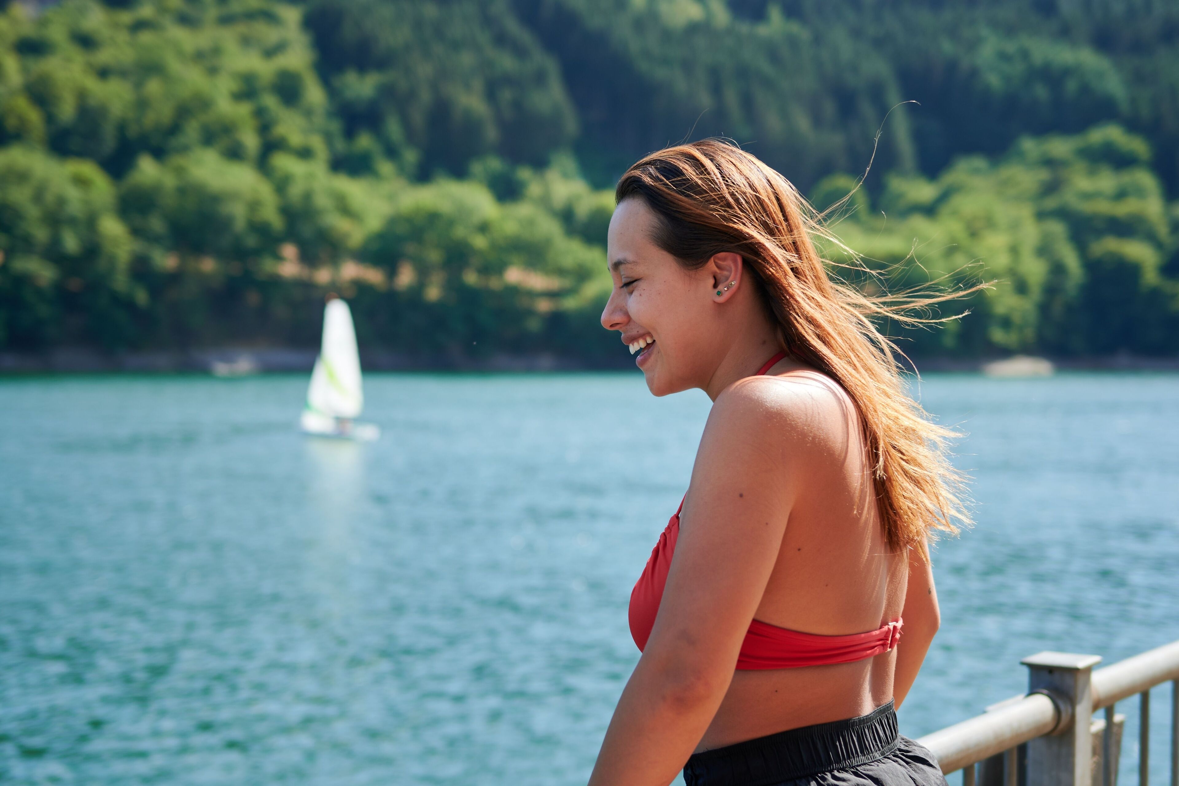 Selective focus shot of a girl leaning on the fence in Lac de la Haute-Sure, Luxemburg