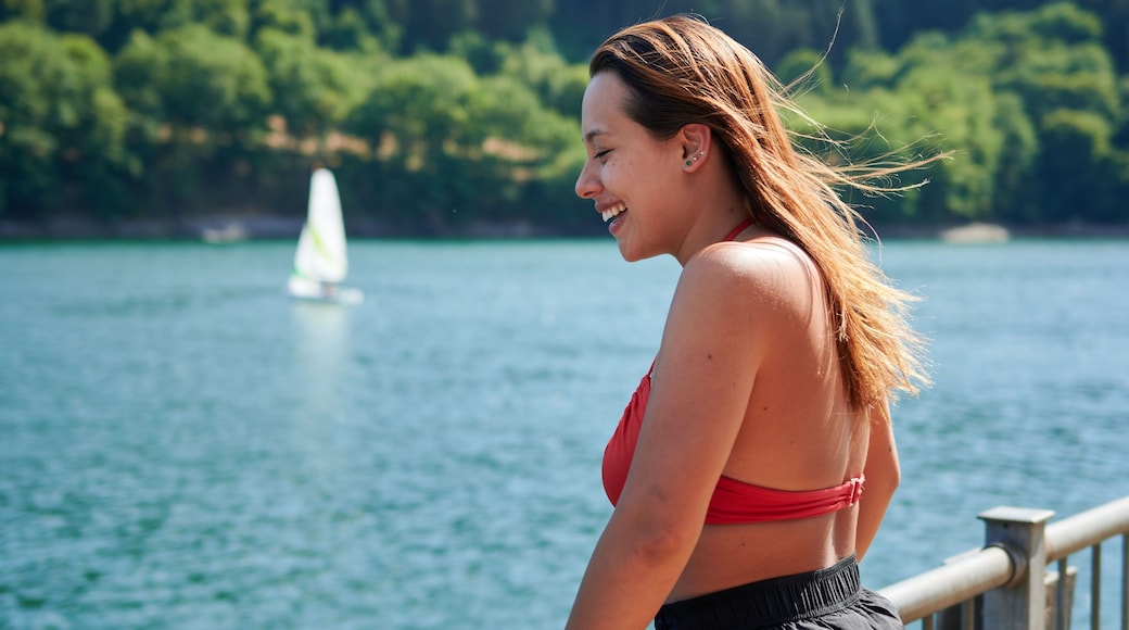 Selective focus shot of a girl leaning on the fence in Lac de la Haute-Sure, Luxemburg