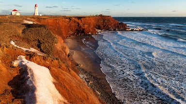 A coastal landscape with a lighthouse, rocky cliffs, and a beach.